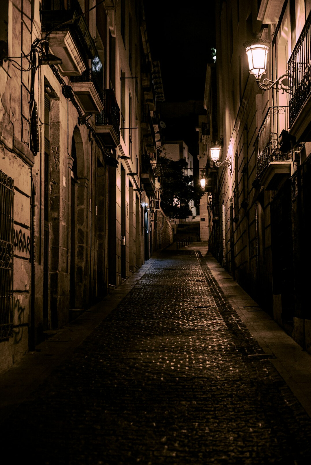 Narrow cobblestone street at dusk with old buildings
