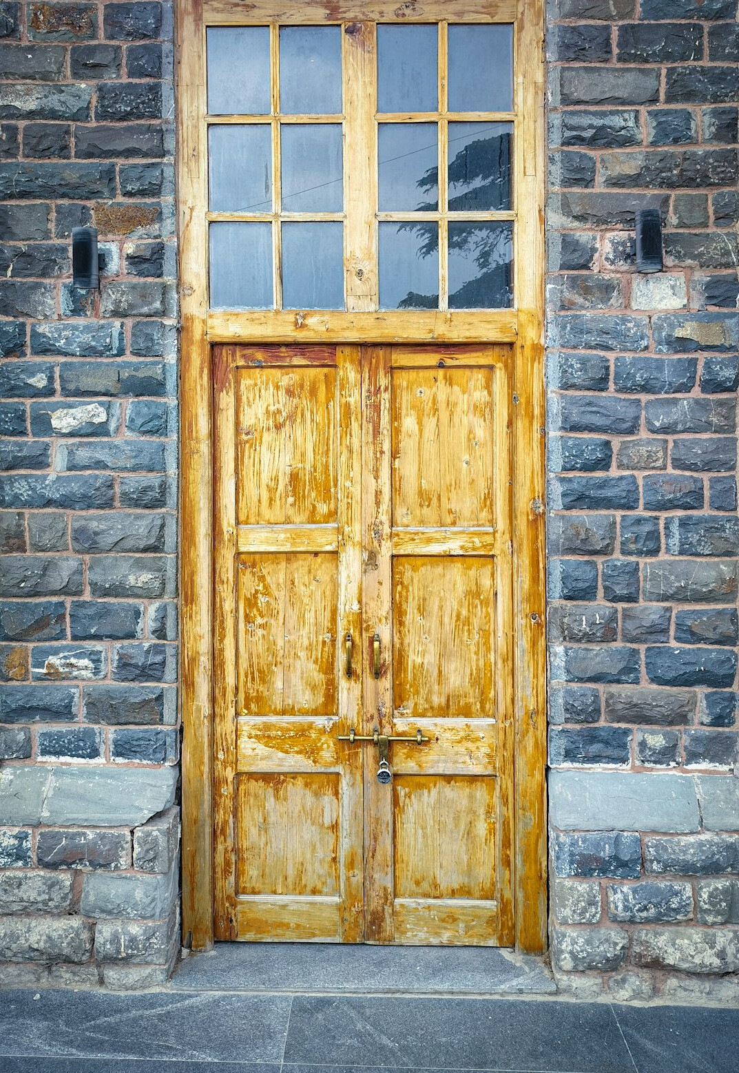 Old wooden door with brass knocker on a stone facade
